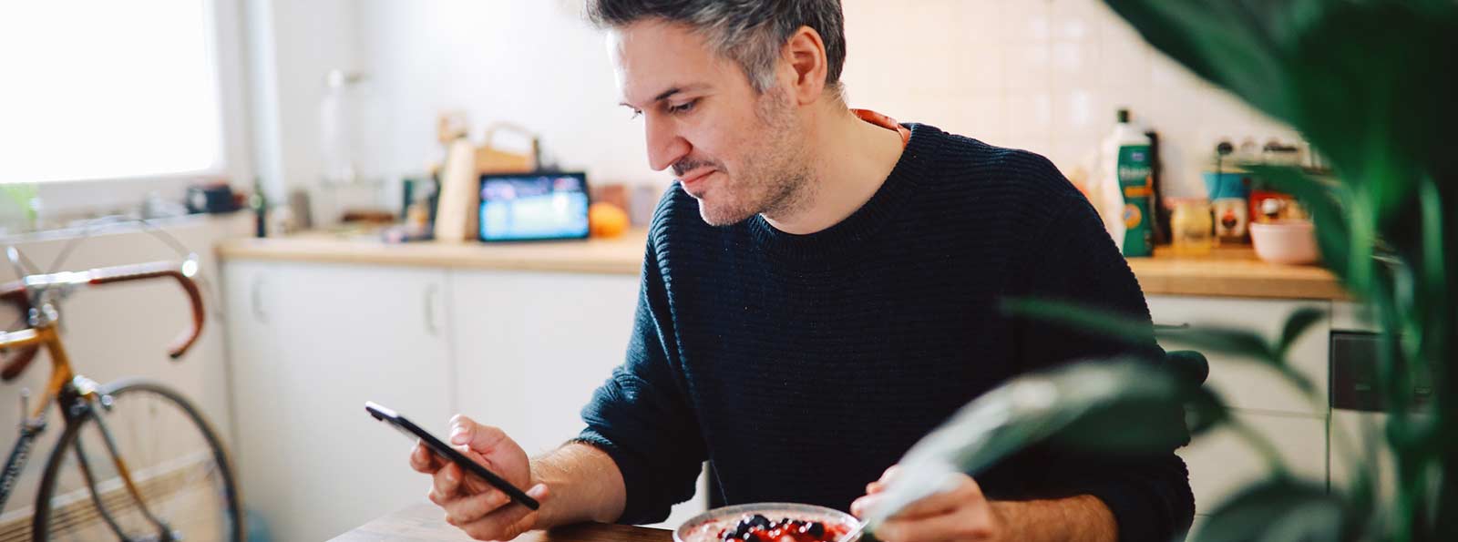 Man holding smart phone at his table while eating breakfast